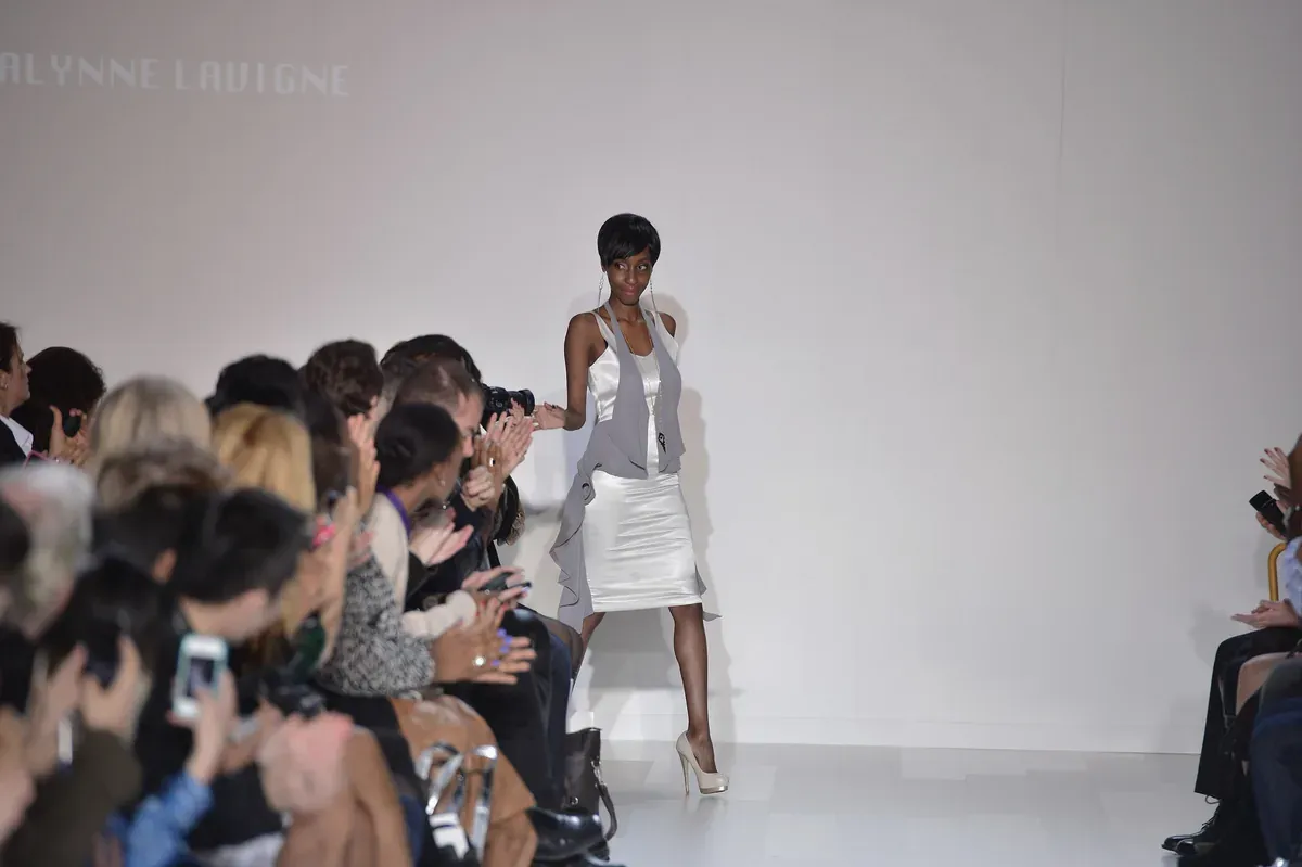 Runway show with a model walking past the audience