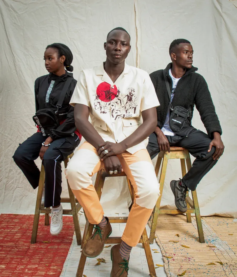 Three people seated on stools against a textured backdrop