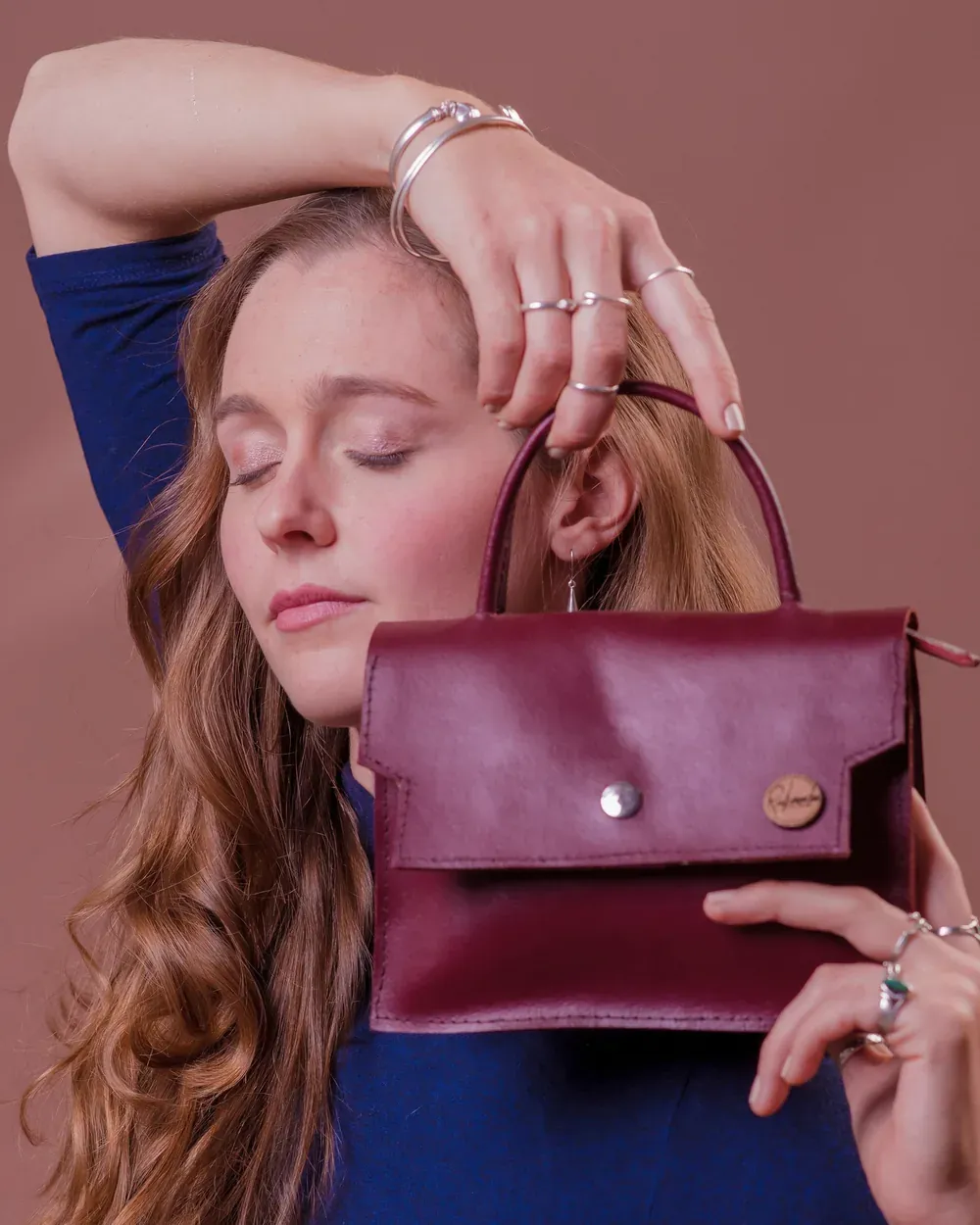 Model holding a burgundy leather handbag