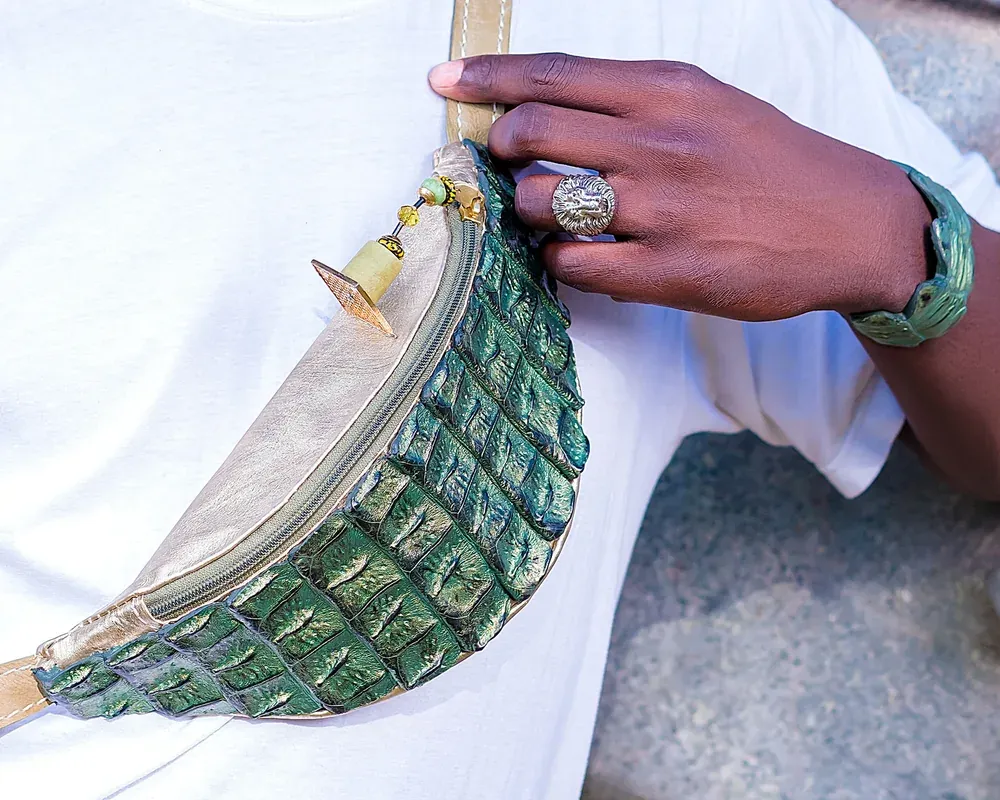 Hand holding a green crocodile pattern waist bag